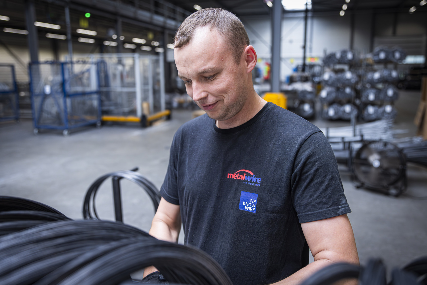 Productiemedewerker controleert rollen industriële draad in de fabriek van Metalwire