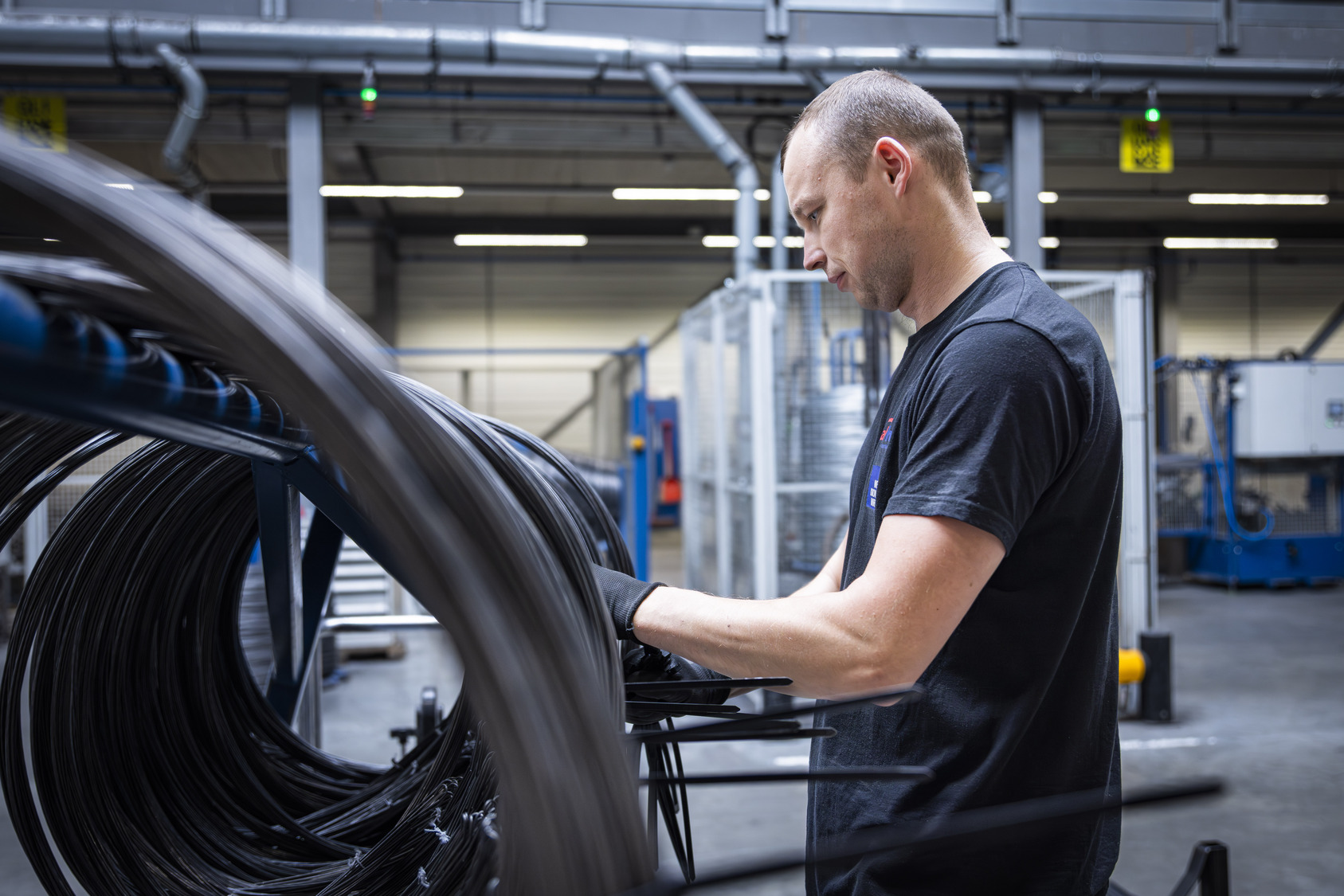 Productiemedewerker controleert rollen industriële draad in de fabriek van Metalwire